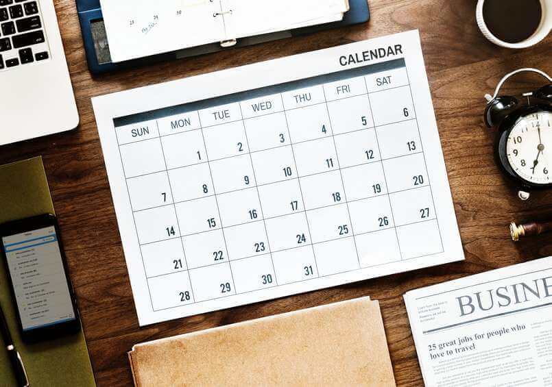 calandar laptop clock phone and business newspaper on desk